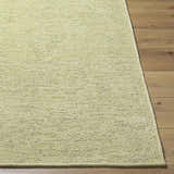 Close-up of the Isako Solid Lime Washable Area Rug showing its woven texture and soft lime green color on wood floor. Front