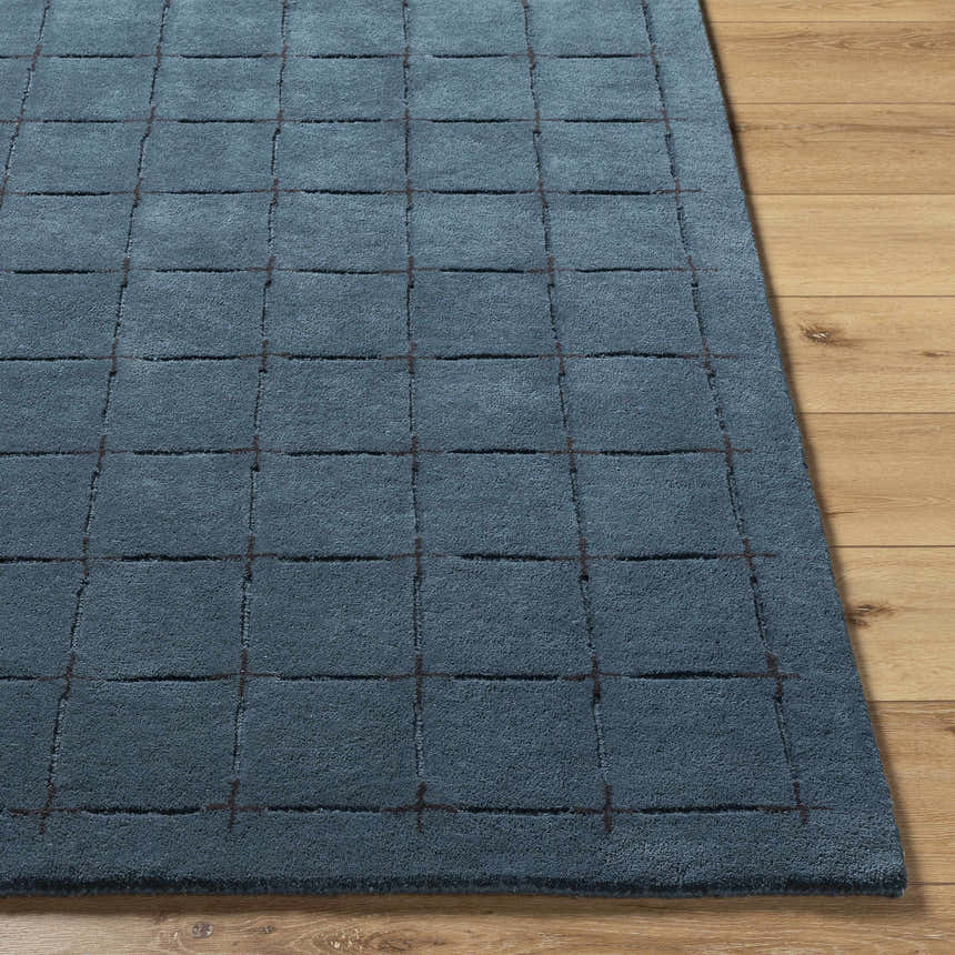 Close-up of the Sanvi Navy Wool Area Rug showing its navy color and contemporary grid pattern on a wood floor. Front