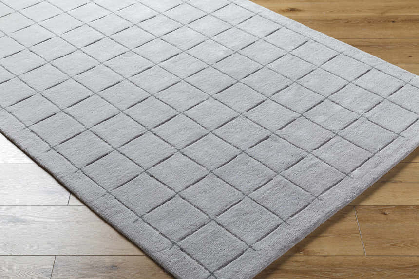 Close-up of the hand-tufted Sanvi Gray Area Rug. Contemporary wool rug with a geometric square pattern. Charcoal and gray tones. Corner