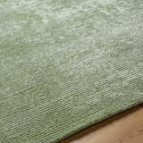 Close up of the sage Helio Area Rug showing its hand tufted texture and subtle linear pattern. Texture