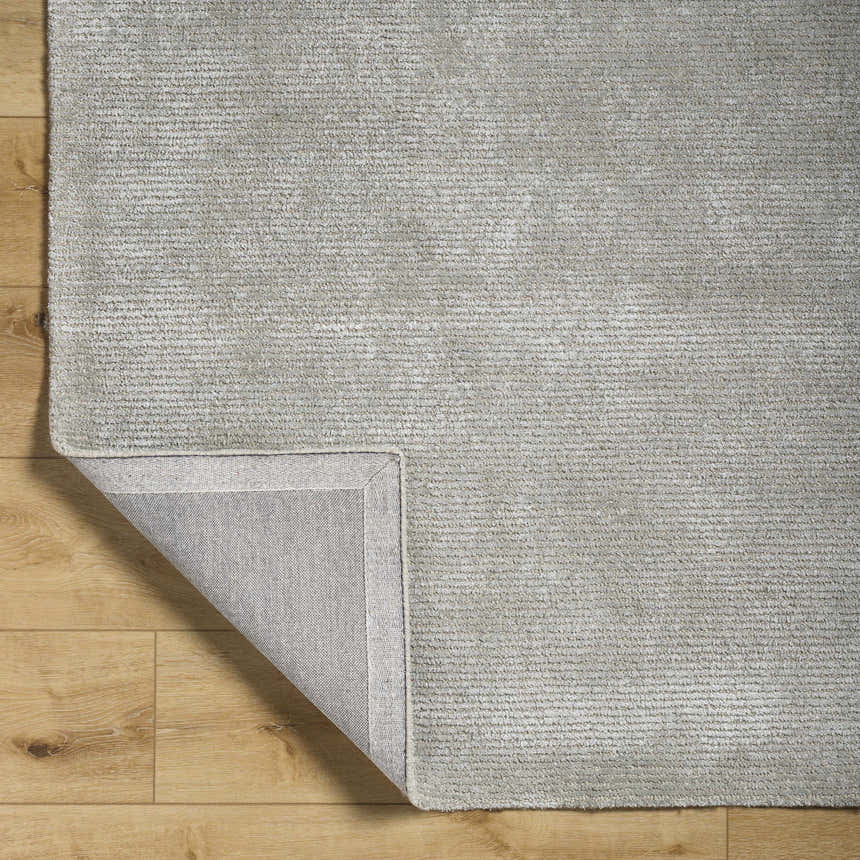 Close up of the hand-tufted Makya Area Rug in metallic silver. Viscose rug with subtle horizontal texture. Fold