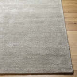 Close-up of the hand-tufted Makya Area Rug. Silver gray viscose rug with a subtle, textured design on wood floors. Front