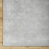 Close up of the hand tufted Noham Area Rug in metallic silver and pale slate on hardwood floor. Corner