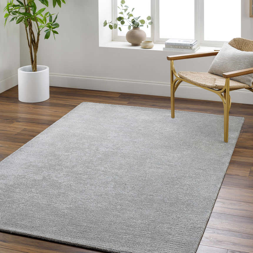 Living room scene with a silver gray Noham Area Rug, wood floors, and a modern chair. Roomscene-Rectangle