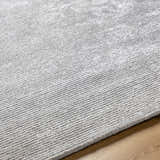 Close up of the hand-tufted Noham Area Rug in metallic silver and pale slate, showing texture and pattern. Texture
