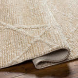 Close-up of the Hosea Cream Area Rug showing its beige color, soft texture, and subtle geometric pattern. Fold