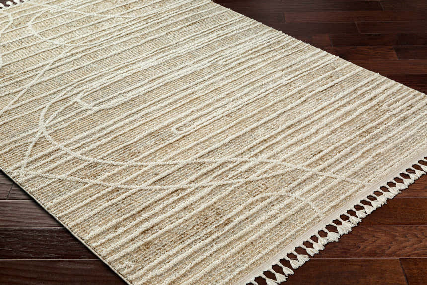 Close-up of the Inaya Area Rug: beige and bone stripes with a subtle geometric pattern and fringe detail on dark wood floor. Corner