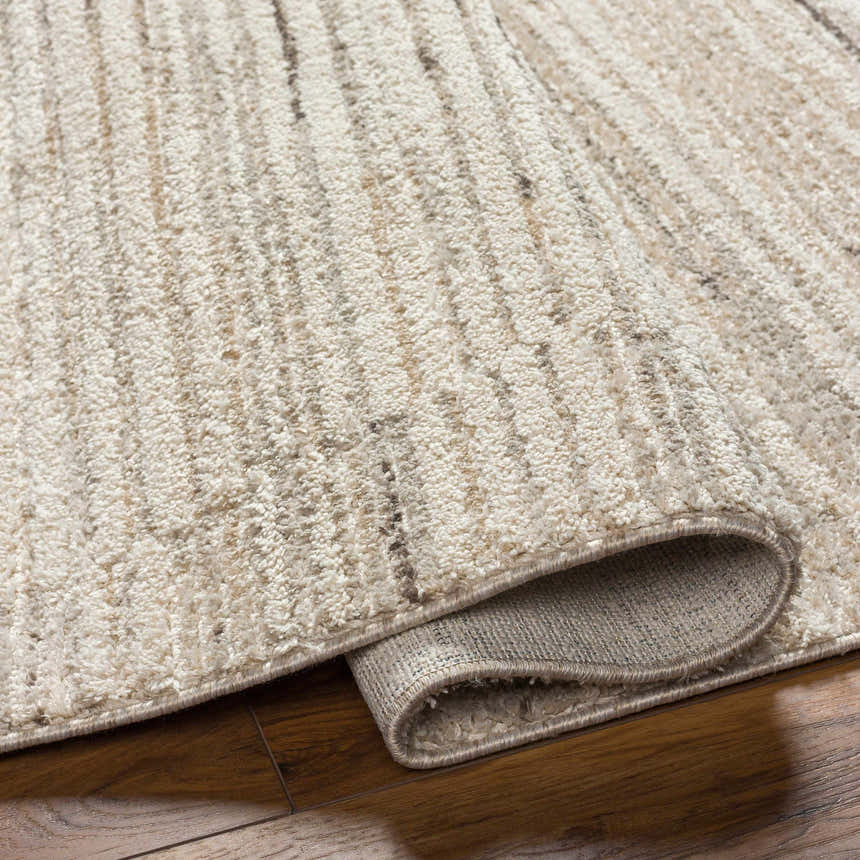 Close-up of the textured Levy Cream Area Rug showing beige, cream, and brown tones and the rug's backing. Fold