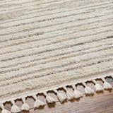 Close-up of the Levy Cream Area Rug showing its beige, brown stripes, soft texture, and decorative tassels. Texture
