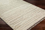 Close up of the Levy Beige Area Rug showing its striped pattern, tassels, and soft texture on dark wood floors. Corner