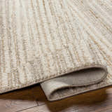Close up of the beige Levy Area Rug showing texture and backing on hardwood floor. Fold