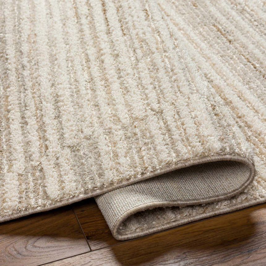 Close up of the beige Levy Area Rug showing texture and backing on hardwood floor. Fold