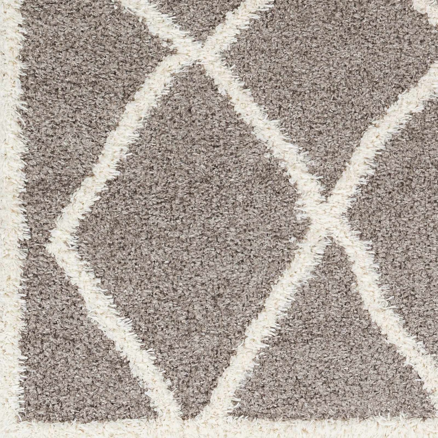 Close-up of the Alkas Area Rug. Dark gray shag rug with a geometric, off-white diamond pattern. Soft, textured polyester. Swatch
