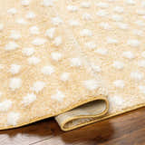 Close-up of the Bernt Beige Polka Dot Area Rug showing the shag texture and white polka dot pattern. Fold