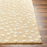 Close-up of the Bernt Beige Polka Dot Area Rug showing shag texture and white polka dot pattern on wood floor. Front