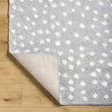 Close up of Bernt Light Slate Area Rug showing light slate shag with raised white dot pattern and rug backing. Fold