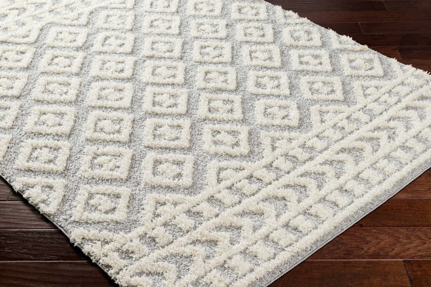 Close-up of the Felix Gray Plush Area Rug showing the geometric shag design and soft texture on dark wood flooring. Corner