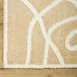 Close up of Gilon Camel Plush Area Rug showing the shag texture and geometric ivory pattern. Corner