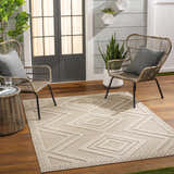 Outdoor patio scene with Aimee Lambswool Area Rug, woven chairs, and wood flooring. Neutral tones create a relaxing vibe. Roomscene-Rectangle