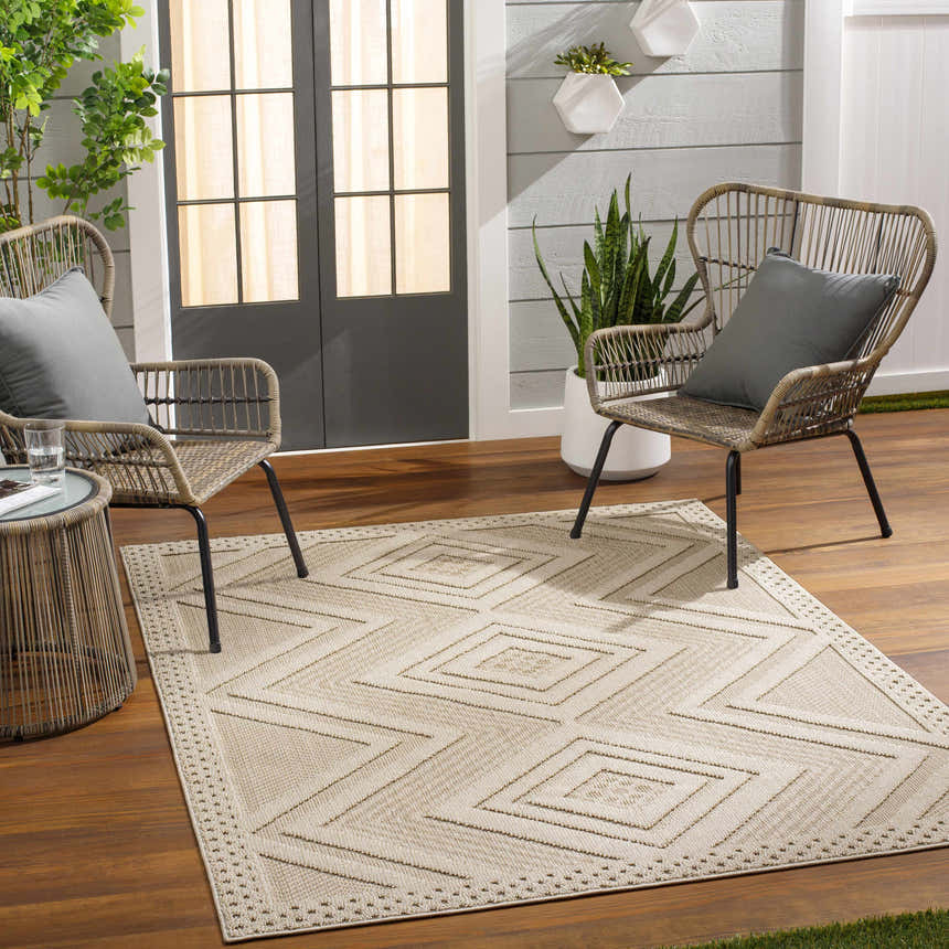 Outdoor patio scene with Aimee Lambswool Area Rug, woven chairs, and wood flooring. Neutral tones create a relaxing vibe. Roomscene-Rectangle