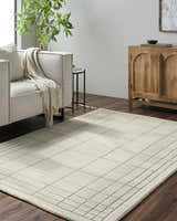 Living room scene with a tan Sedna Wool Area Rug, light gray sofa, and wooden cabinet. Roomscene-Rectangle