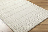 Close-up of the Sedna Wool Area Rug; a hand-tufted, rectangular rug in medium gray and tan with a contemporary grid pattern. Corner
