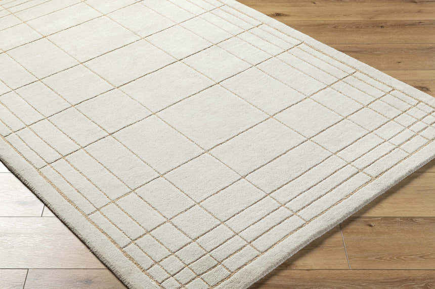 Close-up of the Sedna Wool Area Rug; a hand-tufted, rectangular rug in medium gray and tan with a contemporary grid pattern. Corner