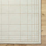 Close-up of the Sedna Wool Area Rug. Medium gray wool with a tan grid pattern on light wood flooring. Corner