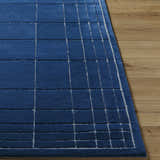 Close-up of the Sedna Navy Wool Area Rug showing its navy color and geometric grid pattern on wood floor. Front