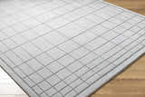 Close-up of Sedna Gray Wool Area Rug. Hand-tufted wool rug with a geometric square pattern in medium gray on wood floor. Corner