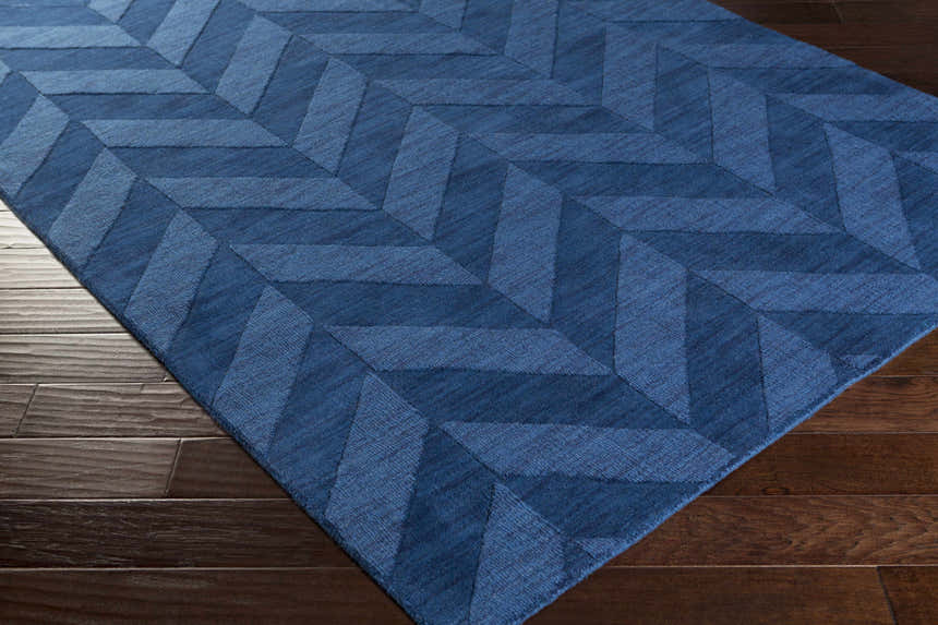Close-up of the navy Searsmont Area Rug on dark wood flooring. Geometric chevron pattern. Clearance rug. Corner