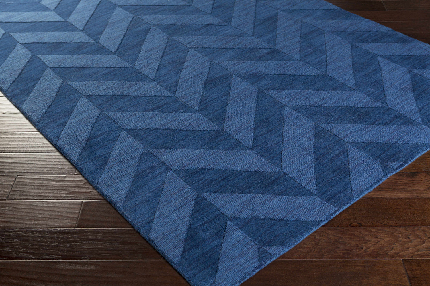 Close-up of the navy Searsmont Area Rug on dark wood flooring. Geometric chevron pattern. Clearance rug. Corner