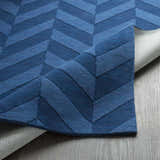 Close-up of the navy Searsmont Area Rug showing its textured chevron pattern and backing on a wood floor. Clearance item. Fold