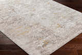 Close-up of the Rama Cream Area Rug showing its abstract beachhouse, gray, and nutmeg pattern on dark wood floors. Corner