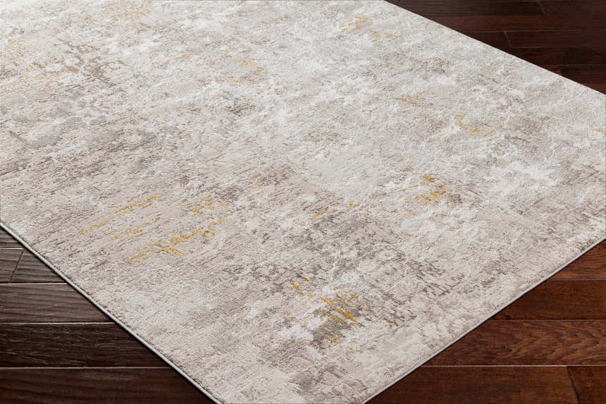 Close-up of the Rama Cream Area Rug showing its abstract beachhouse, gray, and nutmeg pattern on dark wood floors. Corner