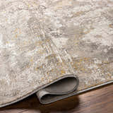 Close-up of the Rama Cream Area Rug showing its abstract design, neutral colors, and soft texture on a wood floor. Fold