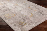 Close-up of the Yuji Area Rug in beachhouse and gray on a dark wood floor. Abstract pattern with nutmeg accents. Corner