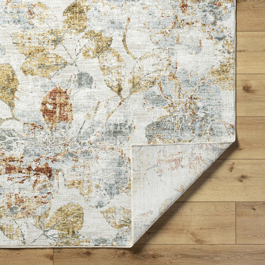 Close up of the Ouida Floral Rug showing a light silver, copper, and gold leaf pattern. Fold