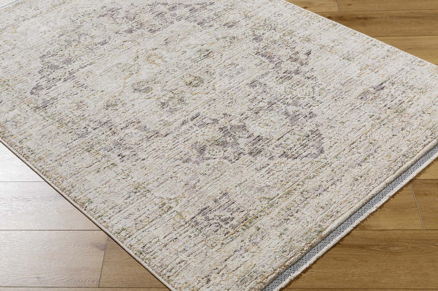 Close-up of the beige Njeri Area Rug with a traditional pattern on a wood floor. Farmhouse style polyester rug. Corner