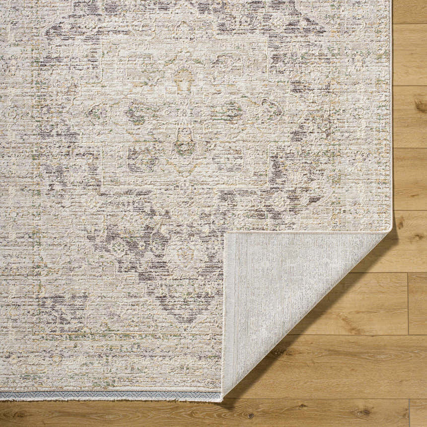 Close-up of the beige Njeri Area Rug showing its traditional pattern and texture on a wood floor. Fold