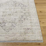 Close-up of the Njeri Area Rug showing its beige, beachhouse colors and traditional pattern on wood flooring. Front
