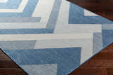Close up of the Adwen Blue Area Rug showing its contemporary geometric pattern and woven texture on dark wood flooring. Corner