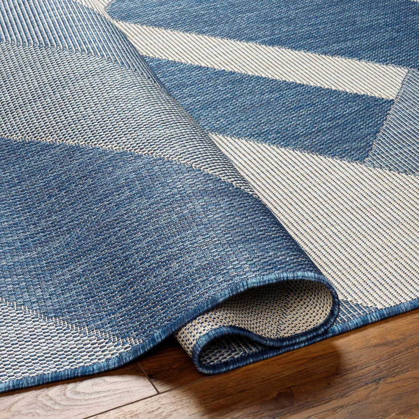 Close-up of the Adwen Blue Area Rug showing its geometric pattern, blue and light gray colors, and woven texture. Fold