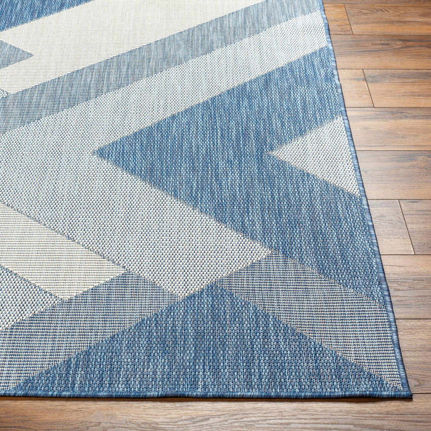 Close up of Adwen Blue Area Rug showing geometric pattern and woven texture on wood floor. Front