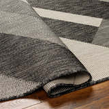 Close-up of the Adwen Gray Area Rug showing its woven texture and geometric pattern in dark and light gray tones. Fold