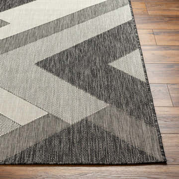 Close-up of the Adwen Gray Area Rug featuring a geometric pattern in dark and light gray on a wood floor. Front
