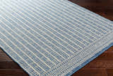 Close-up of the Amena Blue Area Rug showing a geometric block pattern and traditional border on a dark wood floor. Corner