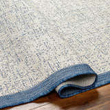 Close-up of the Demas Blue & Cream Area Rug showing its woven texture and contemporary geometric pattern. Fold
