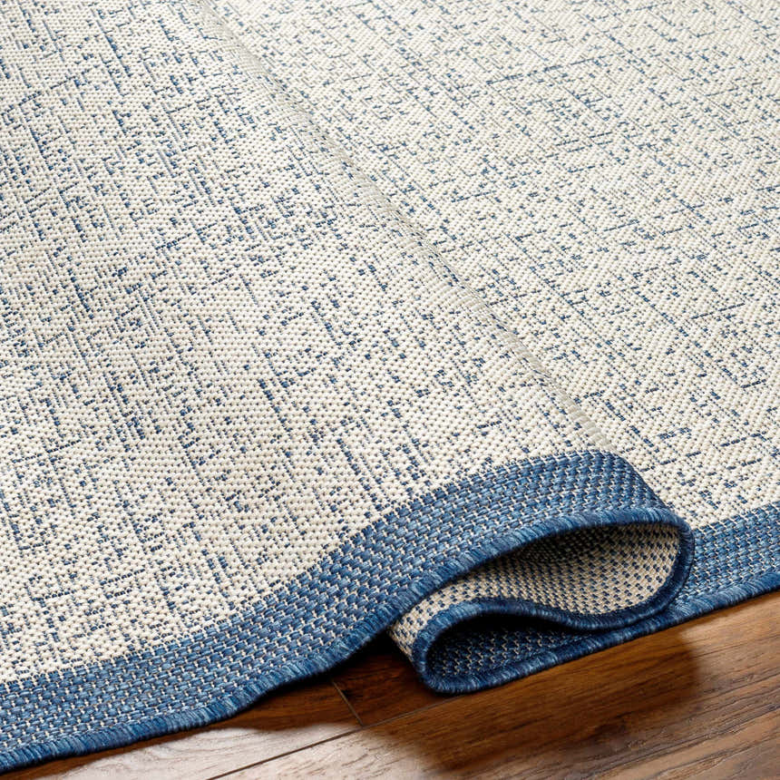 Close-up of the Demas Blue & Cream Area Rug showing its woven texture and contemporary geometric pattern. Fold