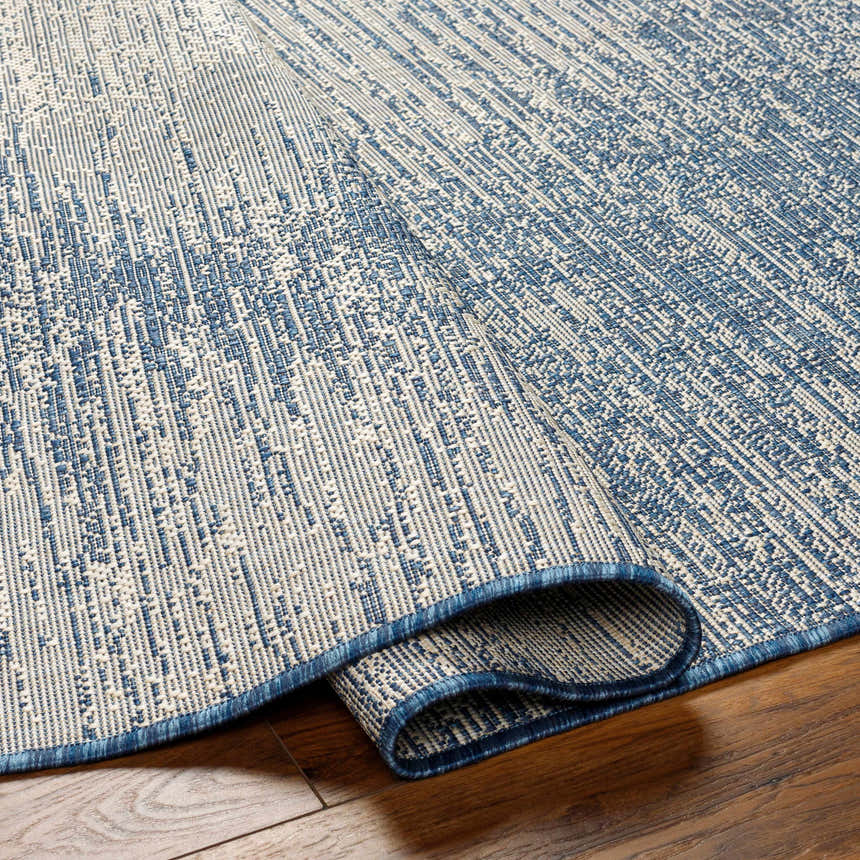 Close-up of the Medi Silver Blue Area Rug showing its texture, abstract pattern, and blue and beige color palette. Fold